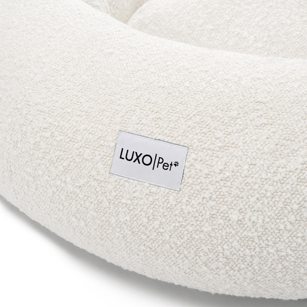 Kyra Medium Boucle Pet Bed – Light Beige Comfort, featuring plush boucle fabric and a supportive, sculpted design with a visible white label, ideal for modern décor and pet relaxation.