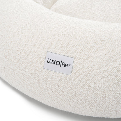 Kyra Medium Boucle Pet Bed – Light Beige Comfort, featuring plush boucle fabric and a supportive, sculpted design with a visible white label, ideal for modern décor and pet relaxation.