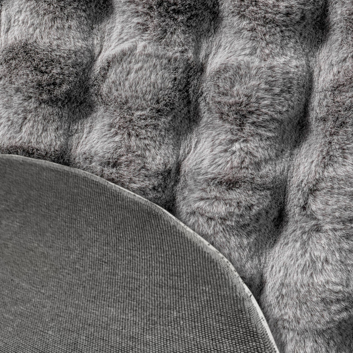 Close-up of the Armida 160cm Round Fluffy Faux Fur Bubble Rug in Grey, showcasing its tufted, shaggy texture with a corner flipped, revealing the plain fabric backing.