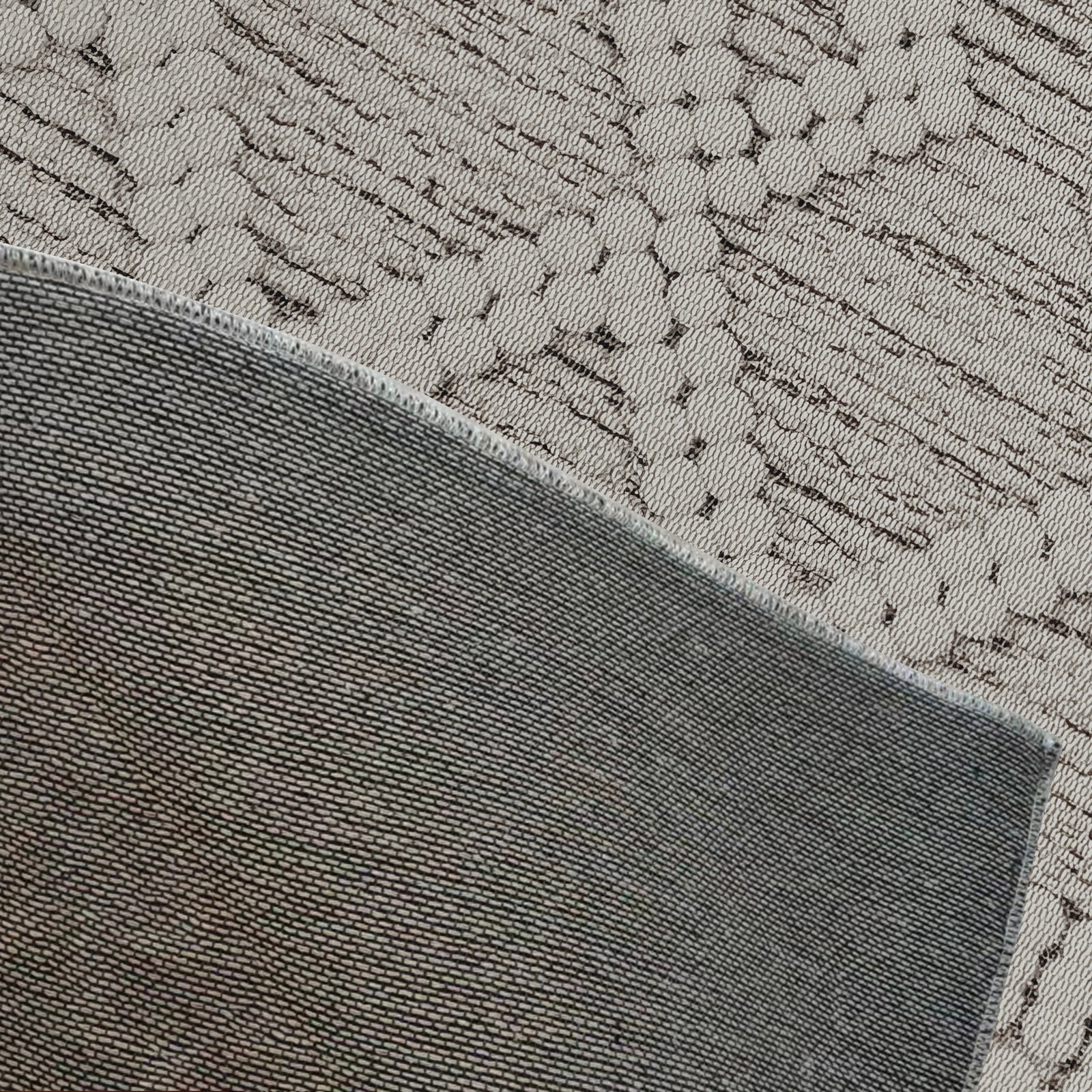 Benita Modern Abstract Tufted Rug 120x180cm featuring a plush, contemporary design with intricate floral patterns, displayed over a solid charcoal-gray textile with stitched edges for contrast.