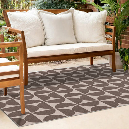 Dolly brown outdoor floor rug with geometric leaf pattern, displayed under wooden outdoor sofa with white cushions. 200 x
