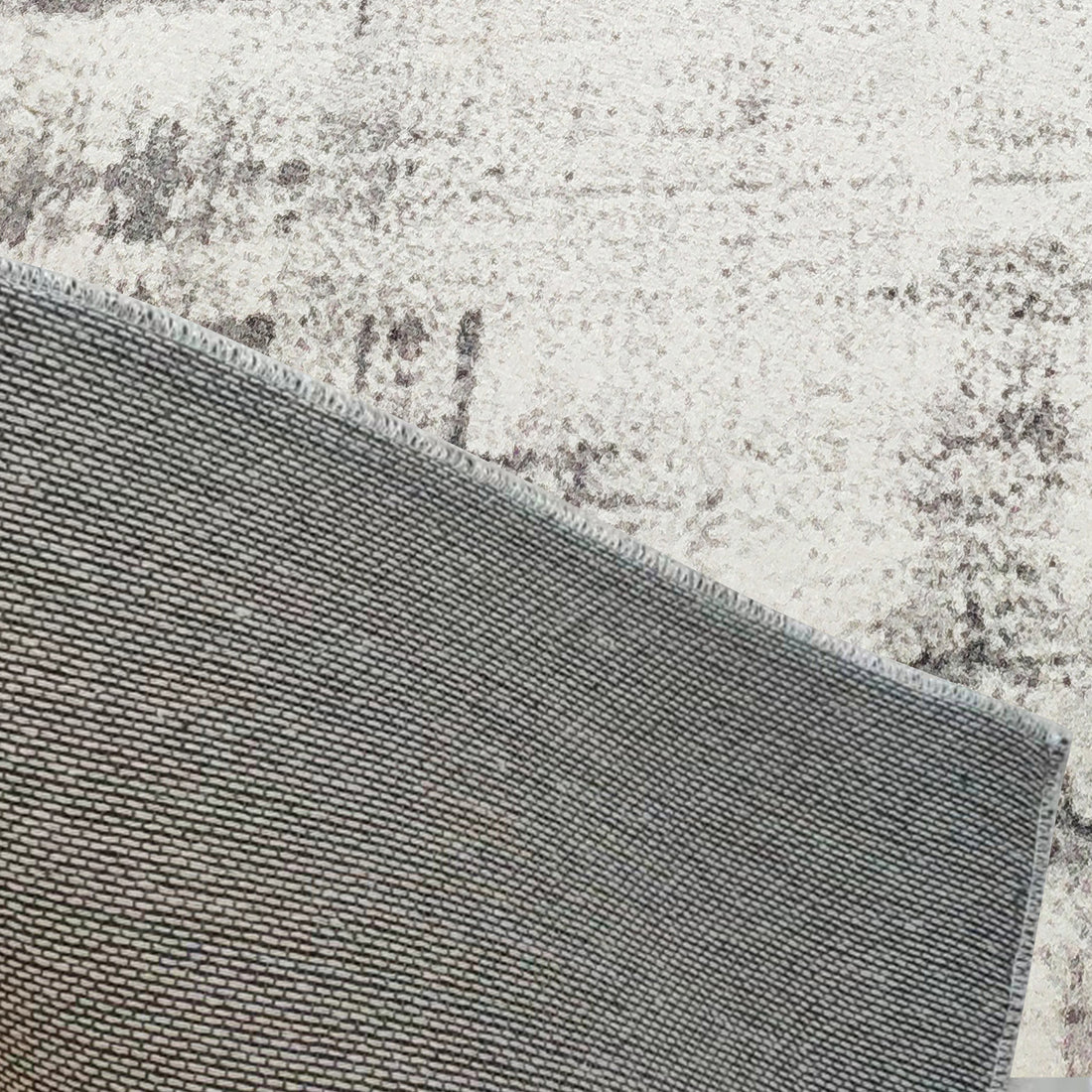 Franco 120x180cm Small Tufted Contemporary Indoor Rug, shown flipped to reveal its non-slip rubber-backed grid, lying on a light-patterned floor, showcasing its durable construction and practical design.