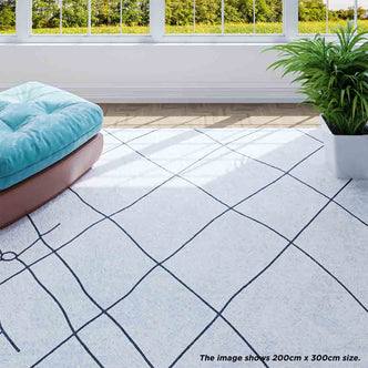 Melody Black & White Modern Rug 160x230cm features abstract black lines on an ivory surface, complementing plants and decor on a tiled floor, perfect for a stylish, minimalist interior.
