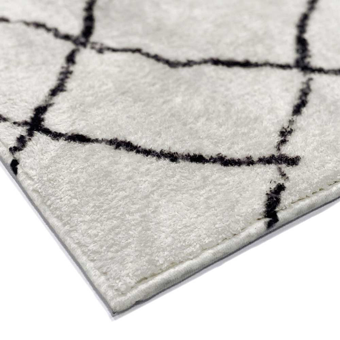 Melody Black and White Modern Floor Rug 200 x 300cm, showcasing a close-up of its cream surface with a black grid pattern, revealing pile texture and edge stitching.