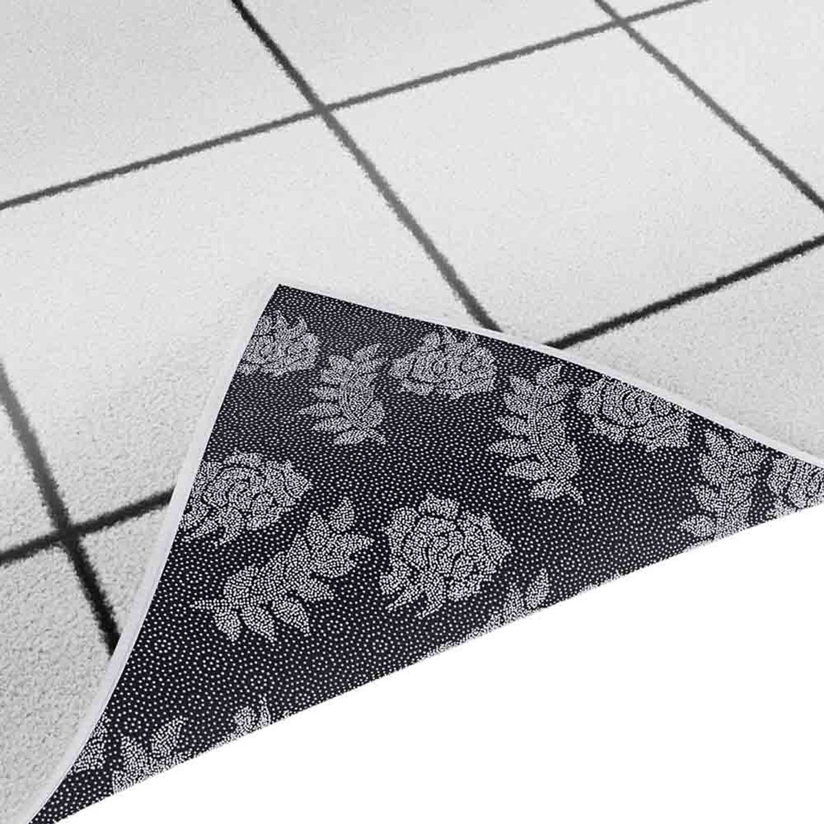 Milani 120x170cm Contemporary Printed Indoor Floor Rug partially flipped, showing a white/gray grid pattern on top and a darker fabric with a dotted-rose design underneath, highlighting its versatile and durable design.