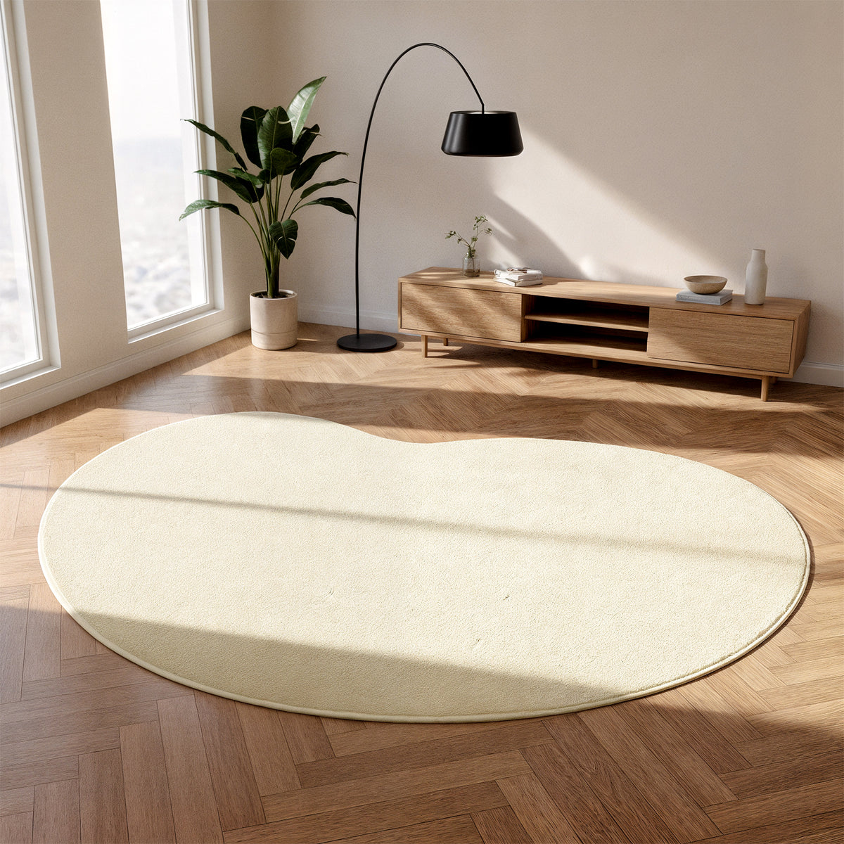 Parna Curved Large Soft Rug in Beige on herringbone wood floor, showcasing its unique organic shape and plush texture, complemented by a mid-century console, arched lamp, and potted plant.