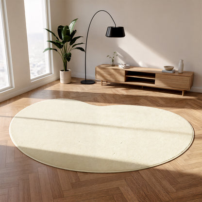 Parna Curved Large Soft Rug in Beige on herringbone wood floor, showcasing its unique organic shape and plush texture, complemented by a mid-century console, arched lamp, and potted plant.
