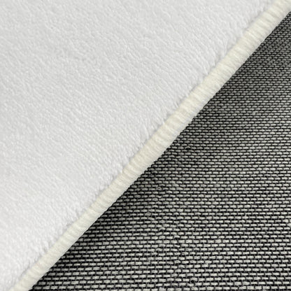 Close-up of the Parna Curved 300x400cm Large Shag Rug in Cream White, showcasing the soft, fleece-like texture folded back to reveal the underlying grayish woven textile.