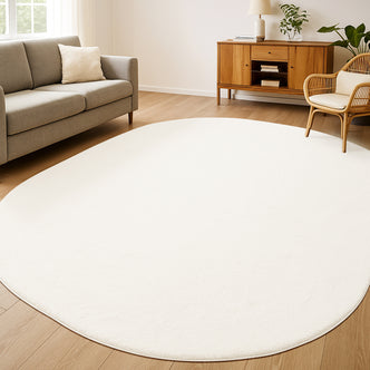 Pavla 300 x 400cm Oval Shaggy Rug in Cream White lies on the floor, creating a cozy atmosphere with its soft, fluffy texture and unique oval shape, complementing the minimalist Scandinavian-inspired living room.