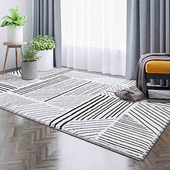 Vikki 200x300cm Large Abstract Contemporary Floor Rug with black geometric patterns on white, enhancing a modern room with wood flooring, sheer curtains, potted plants, and a mustard-yellow bench.