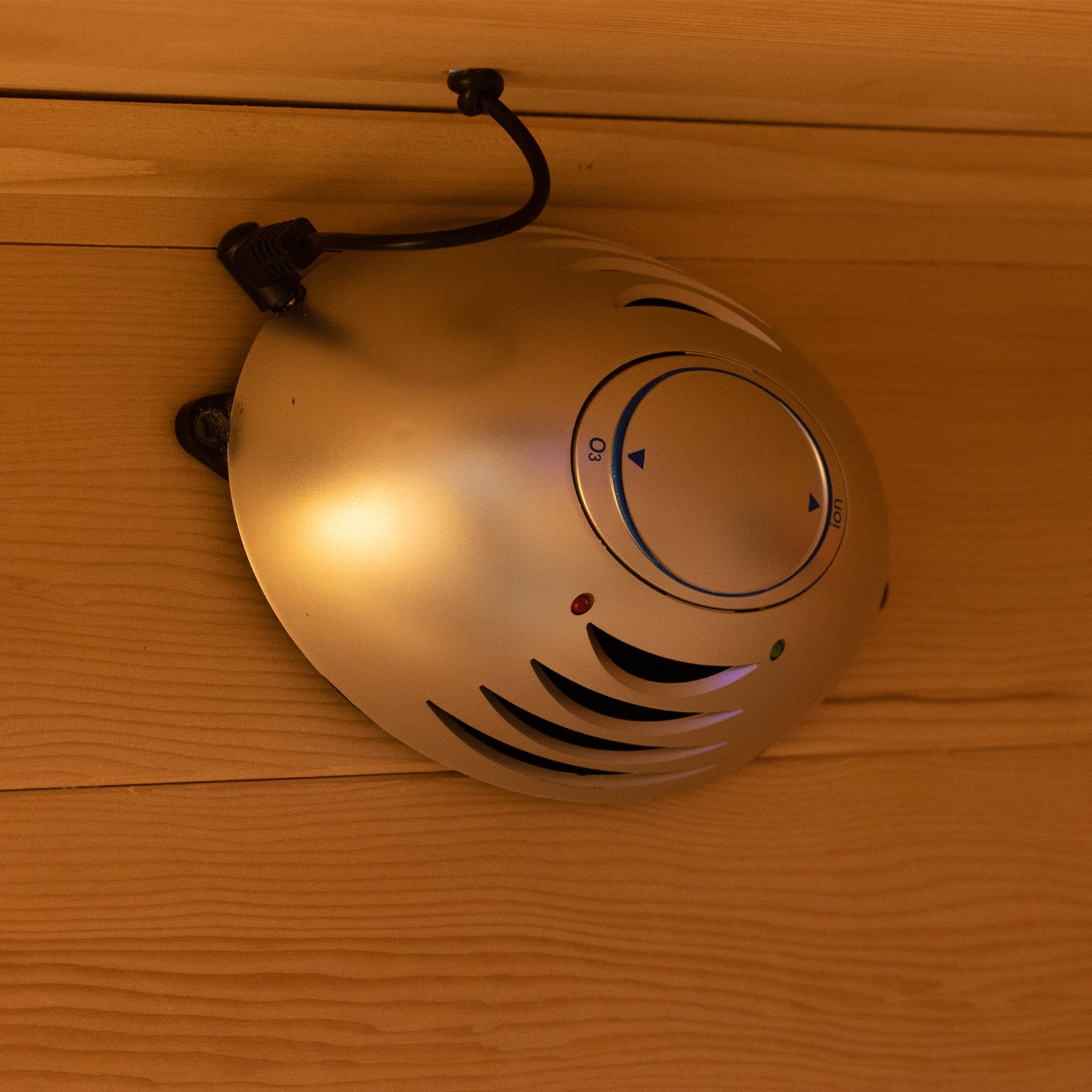 Harlow 1 Person Canadian Hemlock Infrared Home Sauna mounted on wooden paneling, featuring a round silver housing with vents, indicator LEDs, and a dial marked O3 (ozone) and Ion.