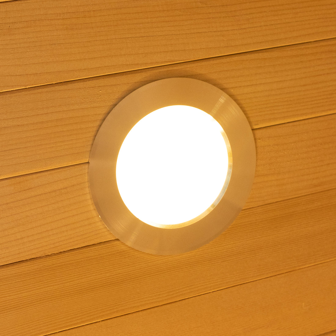 Harlow 2 Person Canadian Hemlock Infrared Home Sauna shown with a round recessed LED downlight in a wood-plank ceiling, creating a warm, inviting atmosphere for relaxation and wellness.