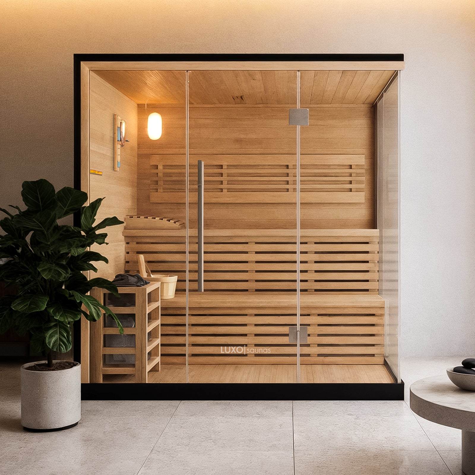 Kivi 4 Person Traditional Stove Finnish Indoor Home Sauna with glass front, wooden benches, a metal-framed heater with stones, a bucket, ladle, and a thermometer inside a minimalist spa-style setting.