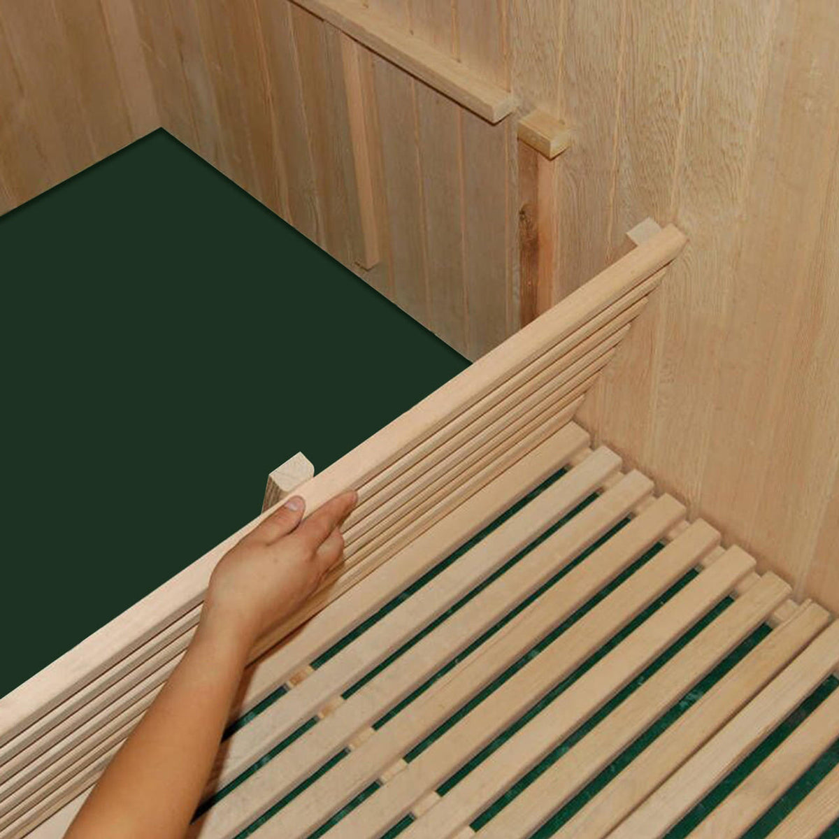 Hand holding a vertical slat of the Kivi 6-Person Traditional Finnish Indoor Home Sauna, showcasing its wooden construction and spacious seating design for a genuine sauna experience.