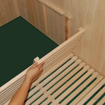 Hand holding a vertical slat of the Kivi 6-Person Traditional Finnish Indoor Home Sauna, showcasing its wooden construction and spacious seating design for a genuine sauna experience.