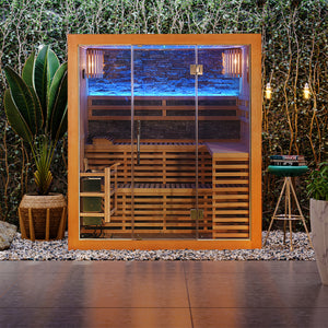 Loyly 3-Person Finnish Steam Home Sauna, a modern outdoor wooden cabin with glass front, reveals tiered benches, blue LED and warm lighting, surrounded by gravel and tropical plants for a spa-like retreat.