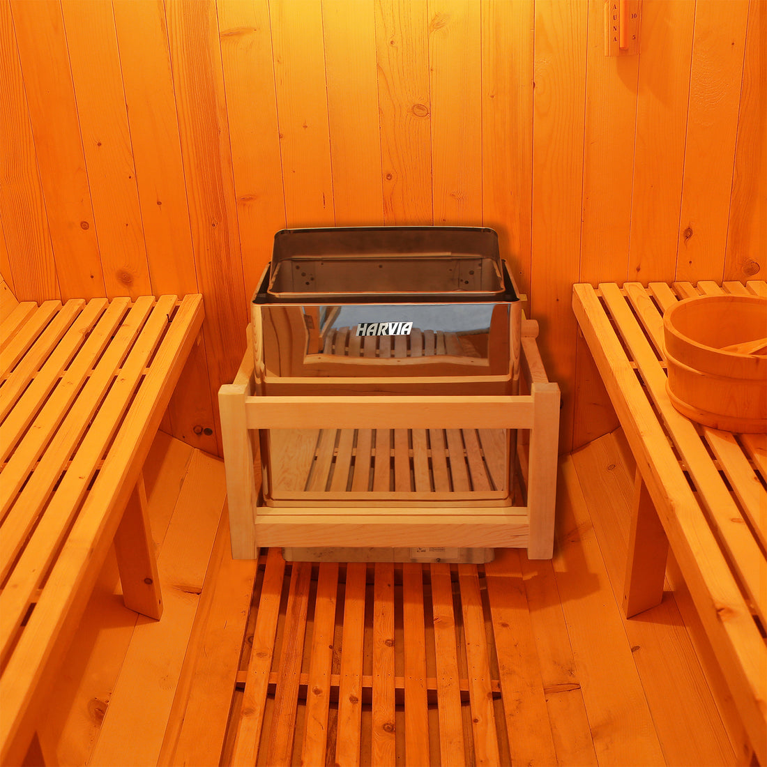 Interior of a Luola 2 Person Pine Outdoor Barrel Sauna & Harvia Stove, featuring slatted wooden benches, a traditional water bucket, and a Harvia electric heater with a wooden guardrail.