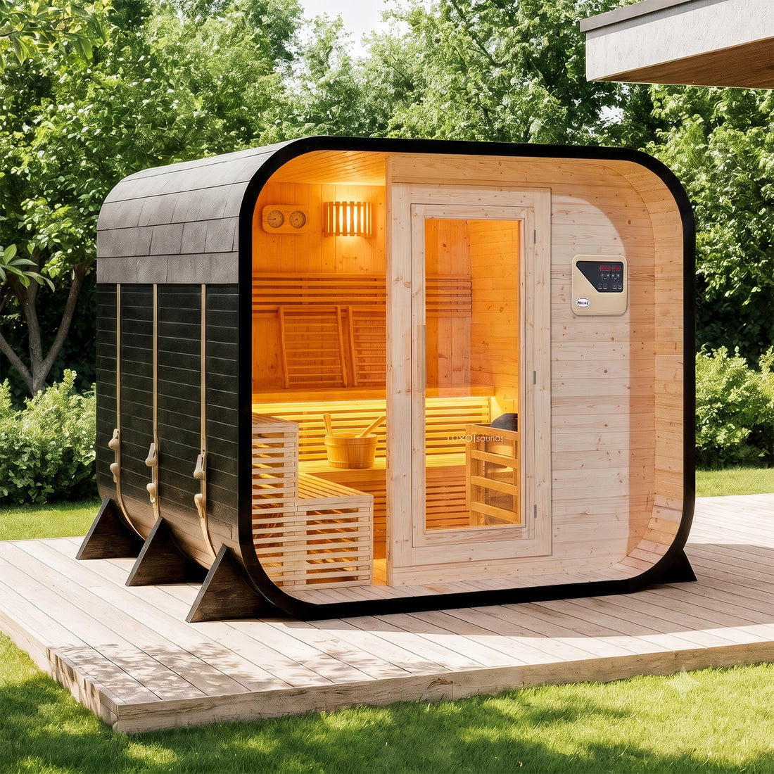 Medika 8 Person Traditional Finnish Outdoor Home Sauna on a wooden deck by a lakeshore, featuring a dark wood exterior, light wood interior, bench seating, and three secure exterior straps.