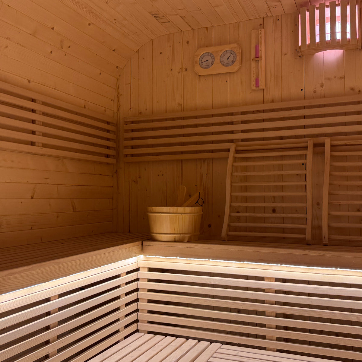 Medika 8 Person Traditional Finnish Outdoor Home Sauna interior showing light wood benches, bucket, thermometer, and LED