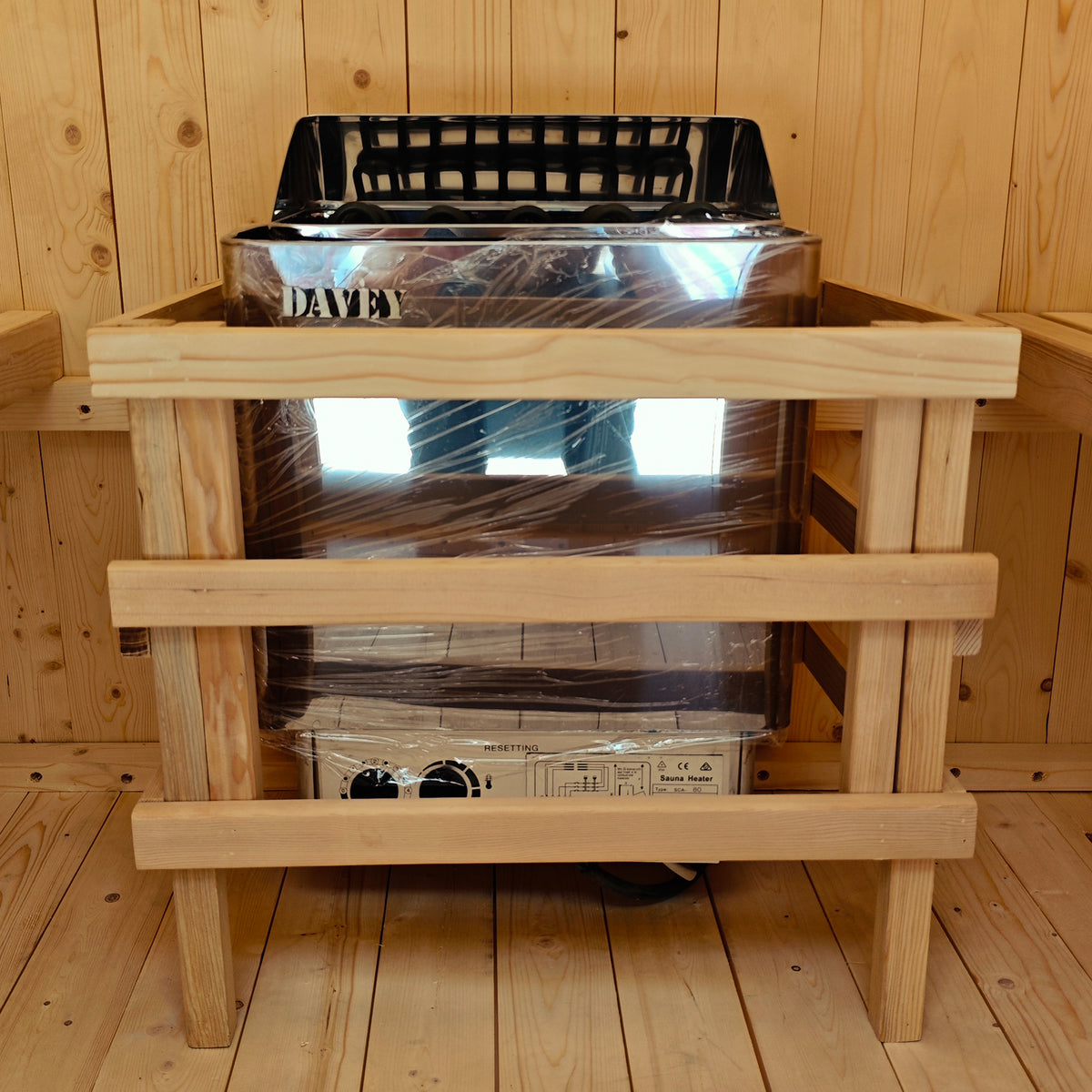 Tarni 2-Person Finnish Outdoor Sauna – Fir Wood features a Davey electric heater with a protective wooden guard, installed in a wood-paneled sauna cabin for backyard relaxation and wellness.