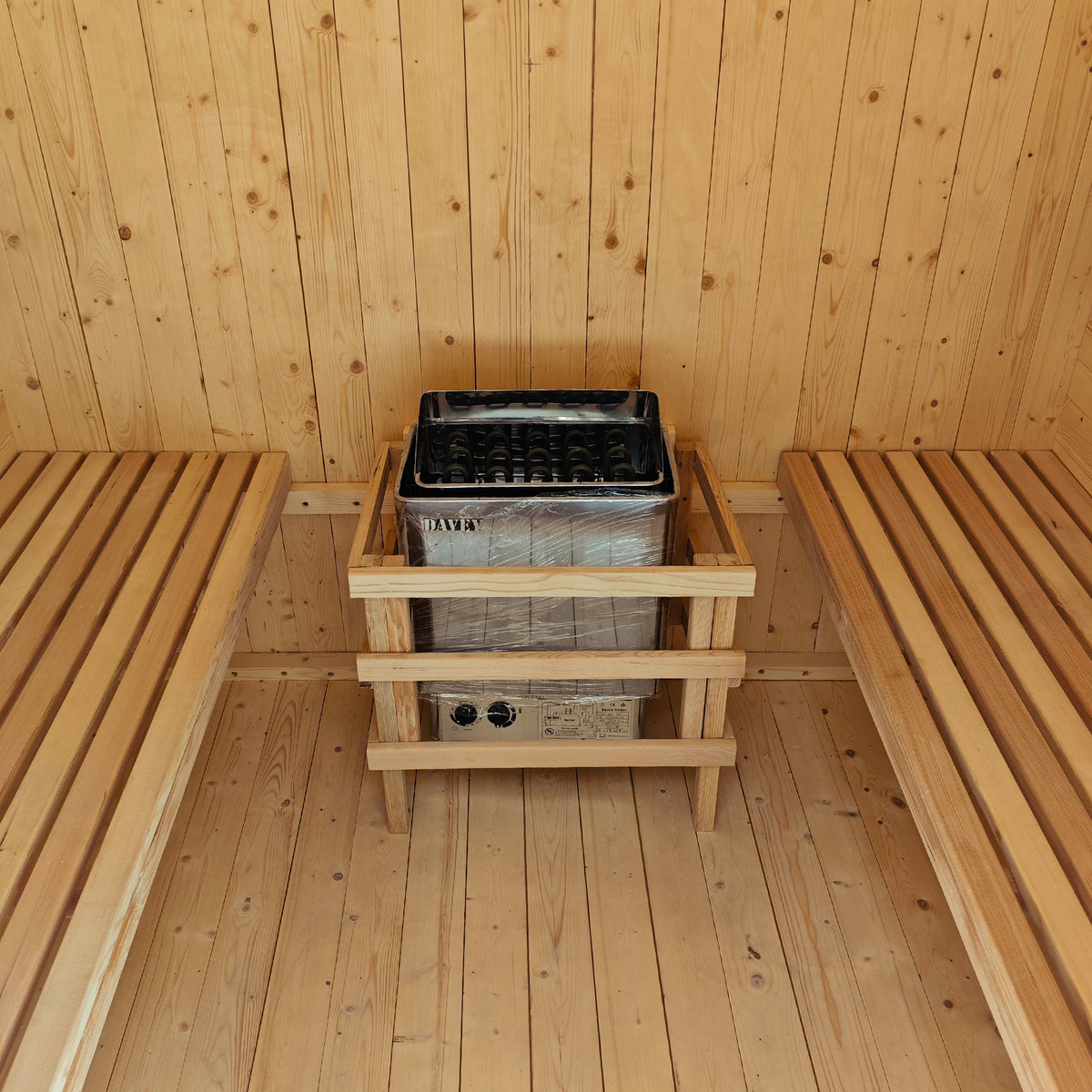 The Tarni 2-Person Finnish Outdoor Sauna – Fir Wood features twin slatted benches and an electric heater with a protective guard, set in a light-colored wood-paneled interior.