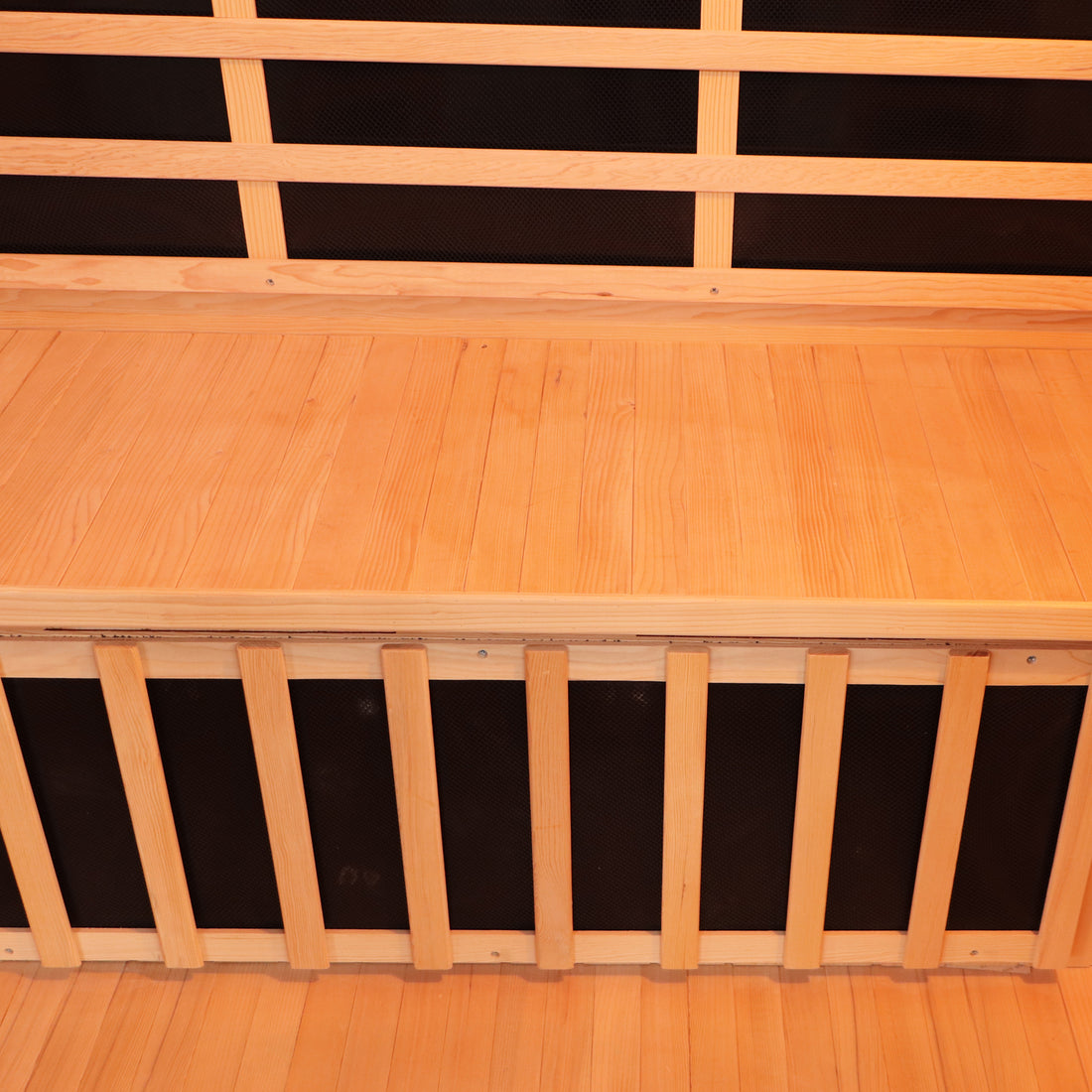 Valo 3 Person Carbon Fibre Infrared Indoor Sauna features light-colored wooden benches with slats and a black backing, resembling a traditional sauna's interior, providing a soothing home relaxation experience.