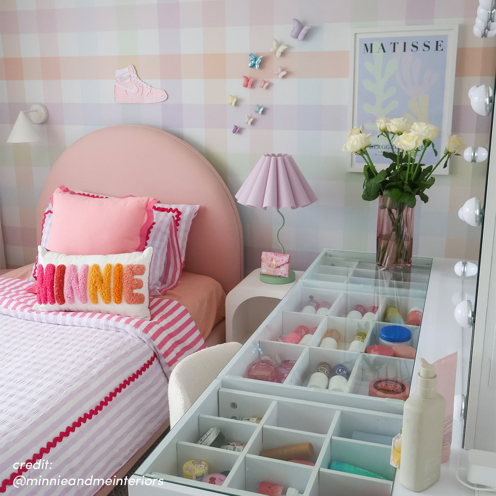 White makeup vanity with open drawer organisers displaying cosmetics, paired with round mirror with LED globe lights