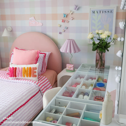 White makeup vanity with open drawer organisers displaying cosmetics, paired with round mirror with LED globe lights