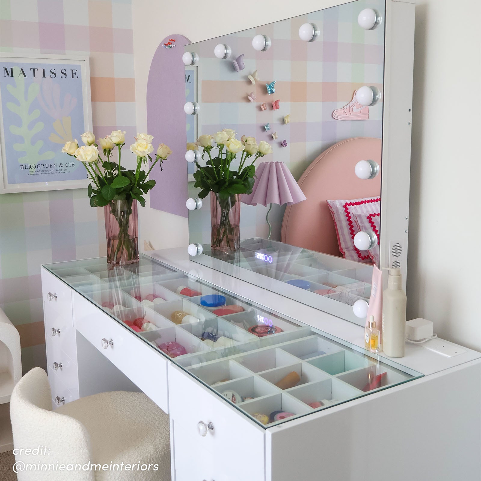 White vanity table with glass top, open drawers, crystal knobs and Hollywood LED mirror reflecting bedroom decor