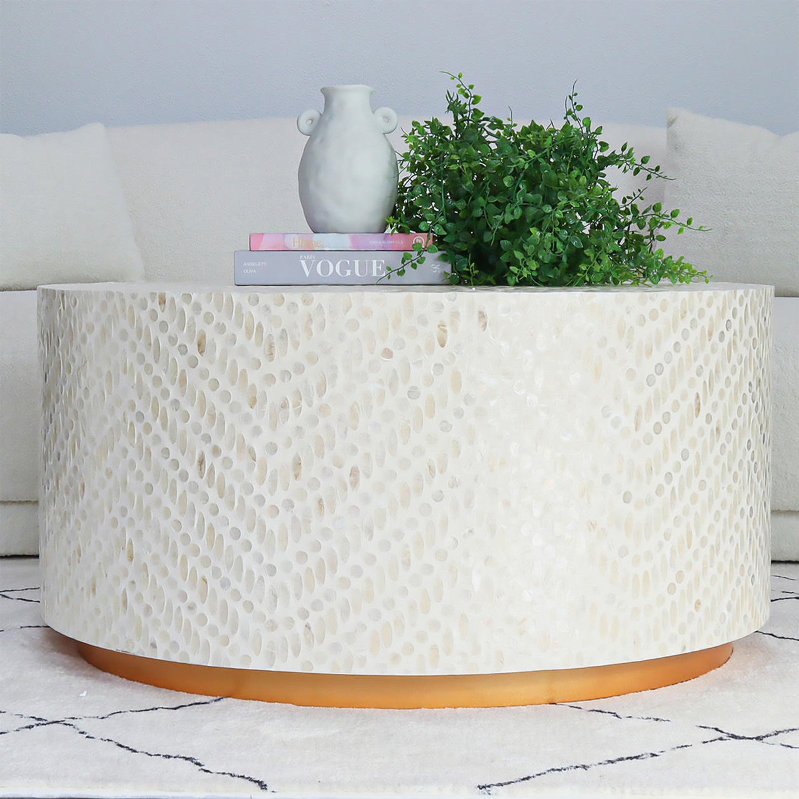 Bisera 91cm Mother of Pearl Inlay Coffee Table features a round top with intricate mother-of-pearl mosaic, situated on a sturdy base, positioned in an elegant indoor setting.