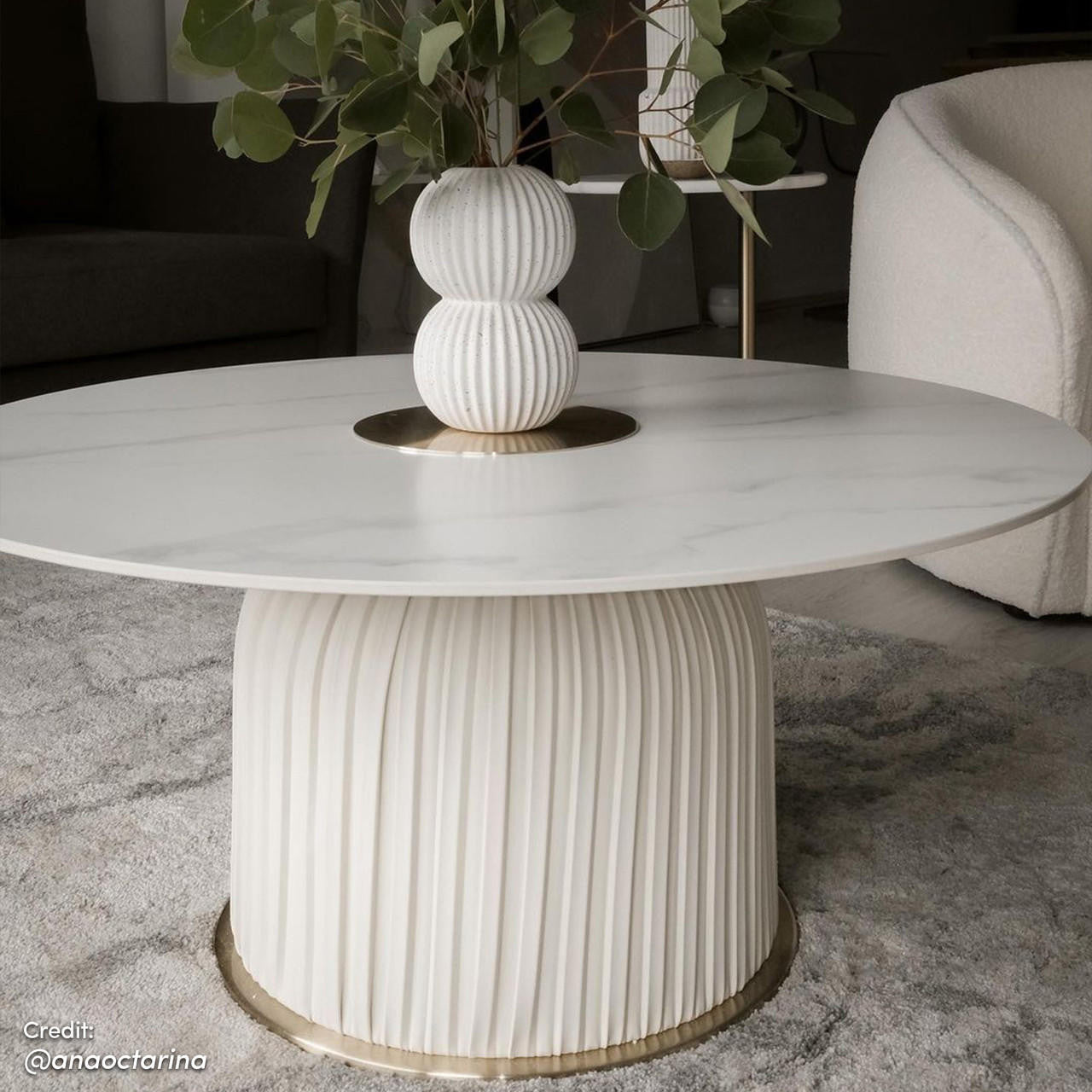 Combee 80cm Sintered Stone Coffee Table Cream White, showcasing a smooth sintered stone top with a unique shape, set against a minimalist backdrop with a white chair and a plant in a vase nearby.