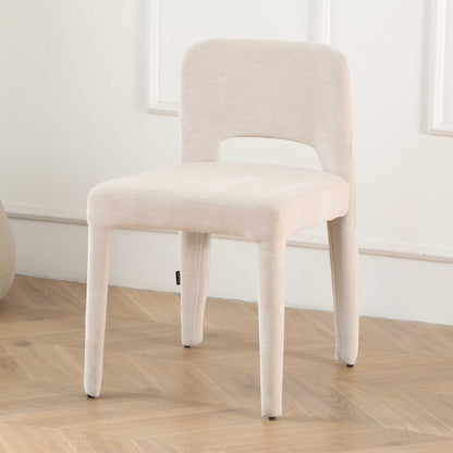 Edris upholstered dining chair in oat with curved backrest, cut-out detail, and fabric-covered legs on herringbone floor