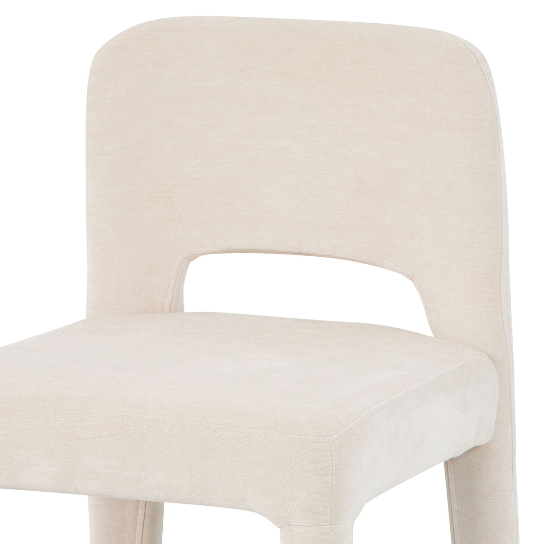 Close-up of Edris dining chair in oat upholstery showing curved backrest with cut-out detail and padded seat