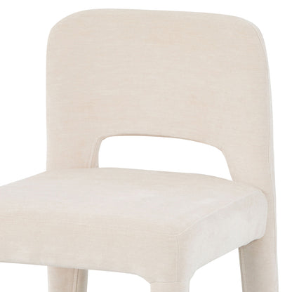 Close-up of Edris dining chair in oat upholstery showing curved backrest with cut-out detail and padded seat