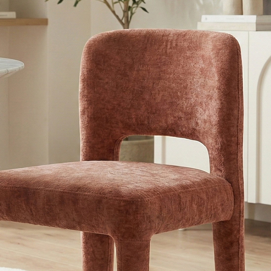 Edris upholstered dining chair in terracotta with curved backrest, cut-out detail and fabric-covered legs