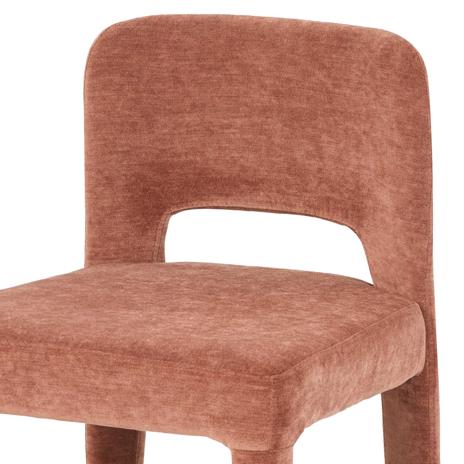 Close-up of terracotta upholstered dining chair with curved backrest and cut-out detail
