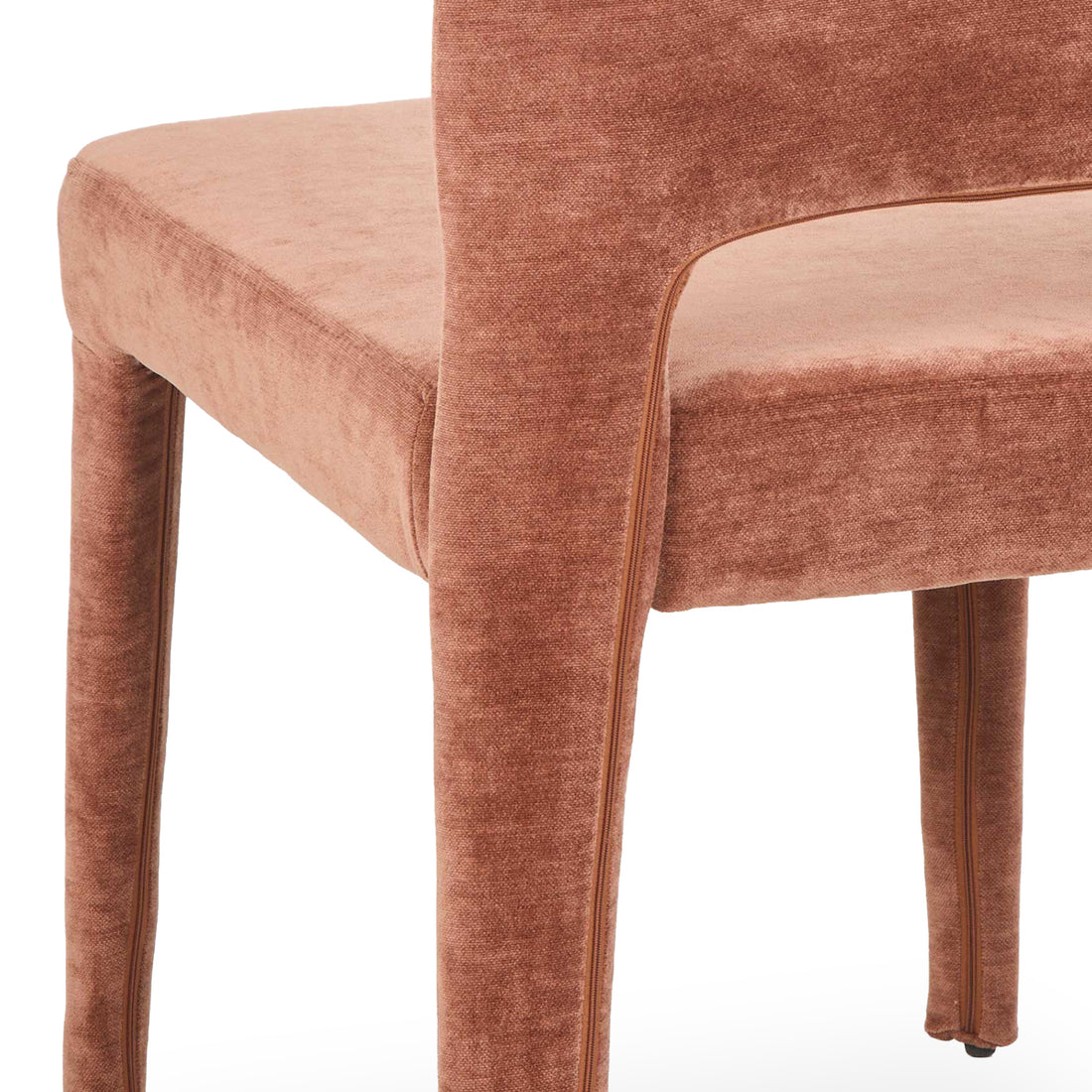 Close-up of terracotta upholstered dining chair showing curved backrest, padded seat, and fabric-covered legs with visible