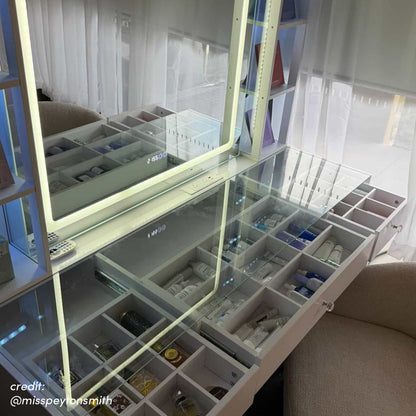 White LED vanity with glass top, open drawers with compartments, and illuminated mirror