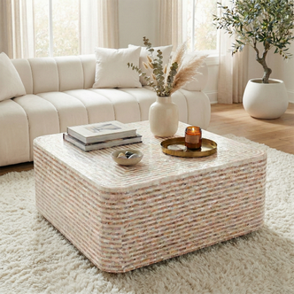 Square mother of pearl coffee table in mocha cream with rounded edges, styled with books, vase and candle on plush white rug