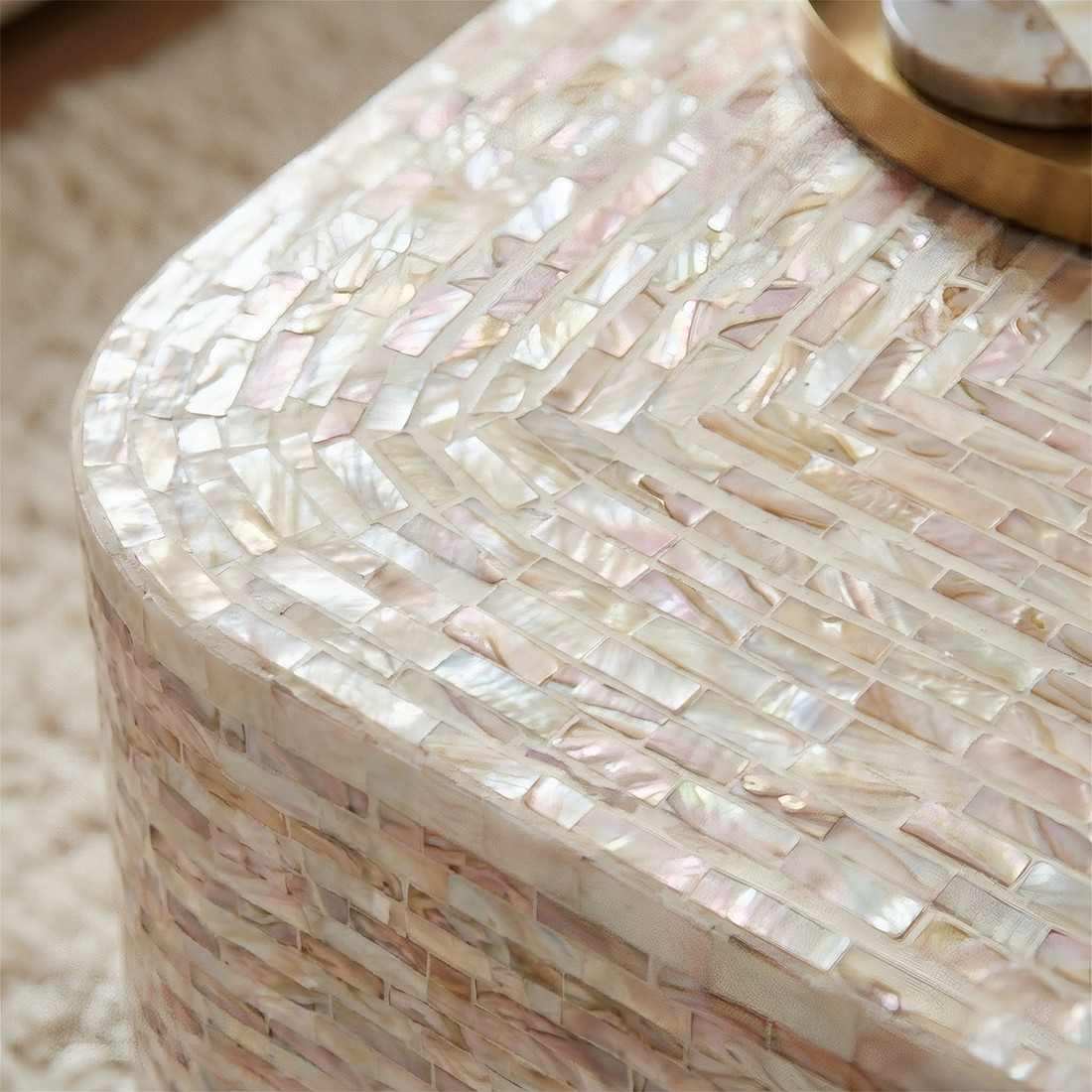 Close-up of mother of pearl mosaic pattern in mocha cream tones on curved coffee table edge