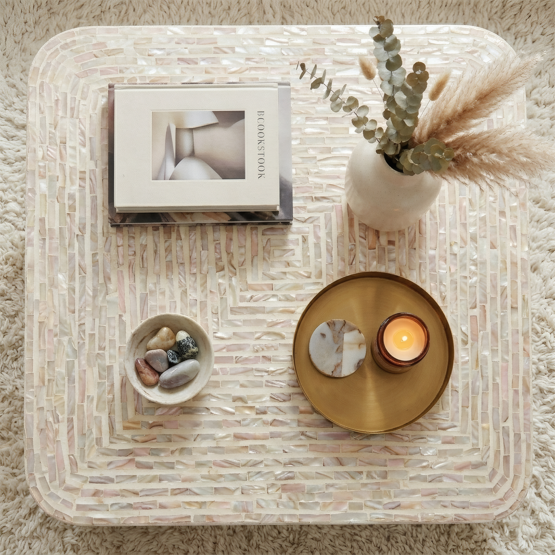 Square mother of pearl coffee table in mocha cream with mosaic tile pattern, styled with books, vase, candle and decorative