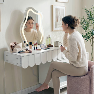 Side profile of a woman using a wavy lit mirror at a white dressing table with acrylic legs.