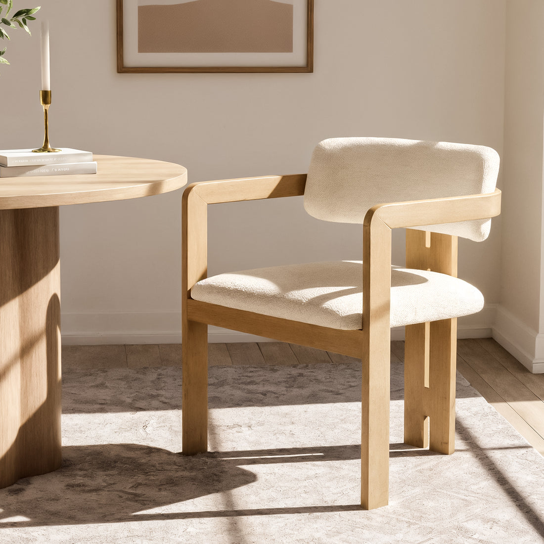 Maddi Boucle Hardwood Dining Chair in Cream White, featuring a light-wood frame with a curved backrest, upholstered in soft boucle fabric, placed beside a round wooden table in a minimalist setting.