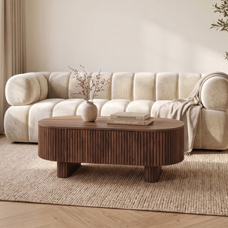 Dark wood oval coffee table styled in a cozy living room with sofa and rug