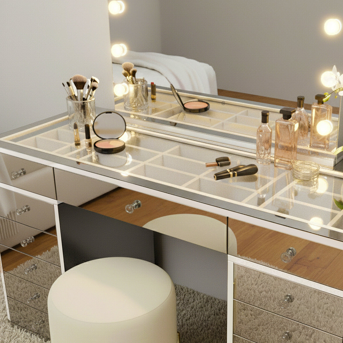 Monroe 13 Drawer Mirror Finish Hollywood LED Dressing Table with mirrored surfaces, makeup brushes, perfumes, and coasters, creating a glamorous, organized vanity setup with an ivory stool and plush rug.