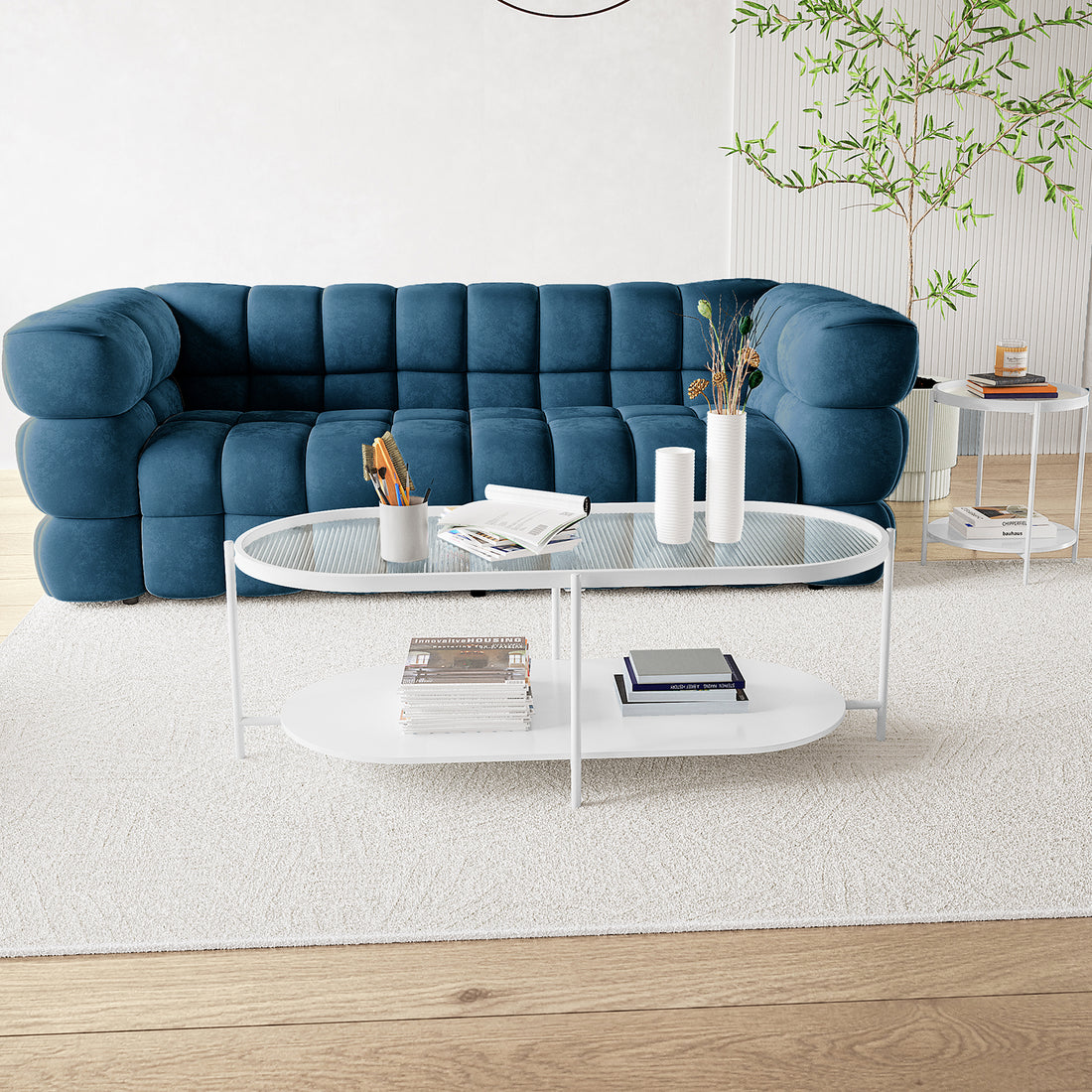 Rebecca Fluted Glass Coffee Table Set White showcasing a stylish design with fluted glass tops on a sturdy metal frame, placed indoors on a round table amidst magazines and books, reflecting modern interior aesthetics.