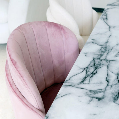 Scarlett Velvet Dining Chair Set of 2 in Mauve Pink, featuring plush channel-back velvet upholstery, is showcased beside a white marble tabletop, with a glimpse of a white boucle-style sofa in the background.