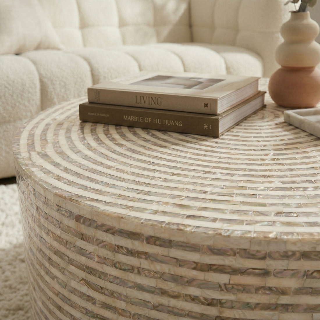 Round mother of pearl coffee table in mocha cream with concentric mosaic tile pattern, styled with two books and a