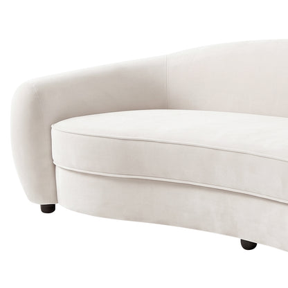 Close-up of curved cream white velvet sofa with rounded armrest, upholstered seat cushion, and black legs on white background