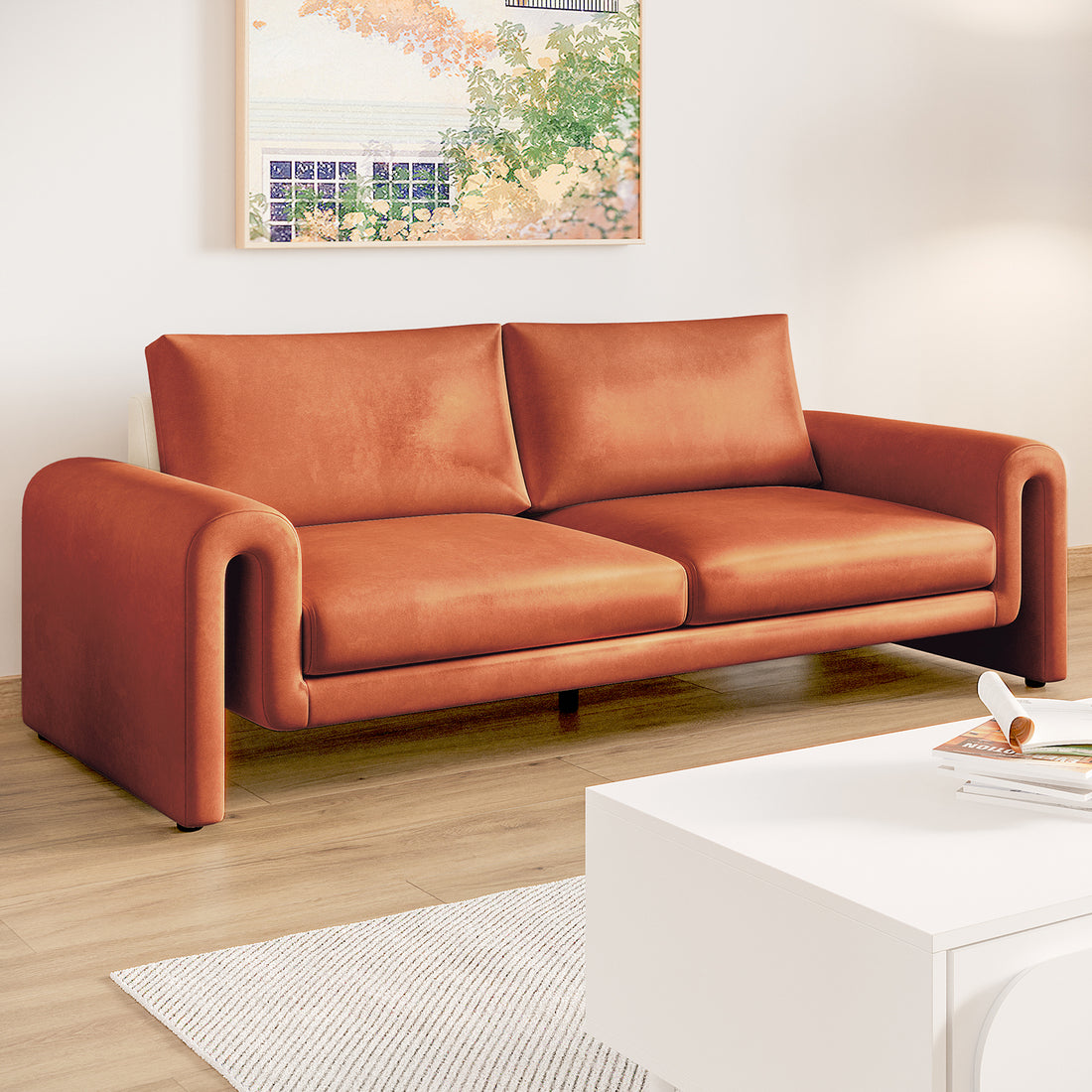 Celyn 3 seater velvet upholstered sofa in burnt orange with curved armrests, shown in a living room with light wood flooring